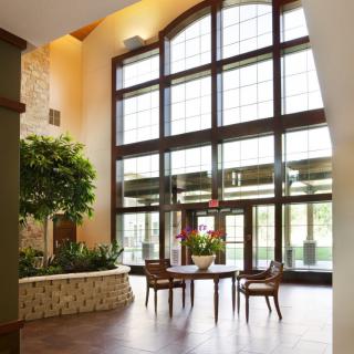 A spacious lobby with large windows, a seating area, and indoor plants, showcasing modern interior design.