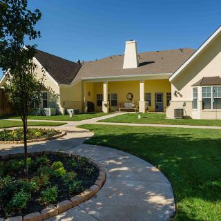 A well-maintained backyard with a garden, lawn, and a curving pathway leading to the house.