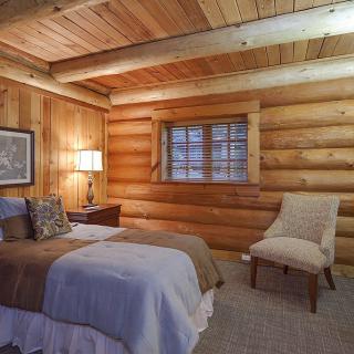 A cozy log cabin bedroom with a rustic wooden interior and comfortable furnishings.