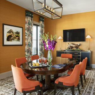 Stylish dining room with orange walls and a round table surrounded by vibrant chairs.