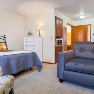 A cozy bedroom with a bed, armchair, and dresser.