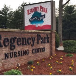 A sign for Regency Park Nursing Center surrounded by landscaped flowers and trees.