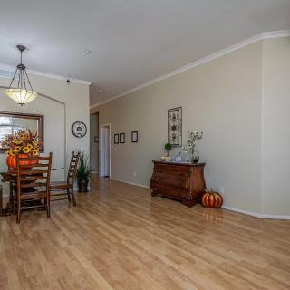 A spacious dining room with wood flooring, featuring a decorated table and elegant chandelier.