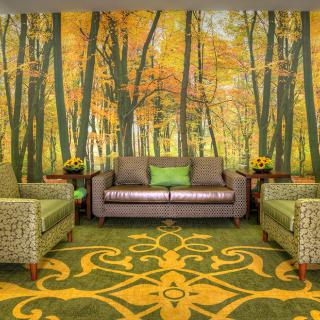 A cozy living room featuring a forest-themed mural with autumn colors, complemented by comfortable seating and a nature-inspired carpet design.