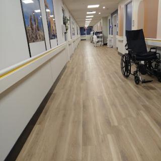 A quiet corridor in a healthcare facility, featuring a wheelchair and well-lit surroundings.