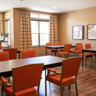 A well-lit conference room with orange chairs and dark tables arranged for a meeting.