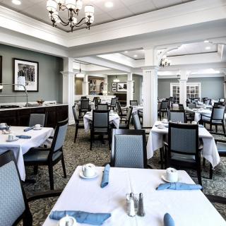 An elegant dining area with neatly arranged tables and chairs, featuring a chandelier and tasteful decor.