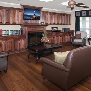 A cozy living room featuring wooden cabinets, a fireplace, and comfortable seating with a television above the mantel.