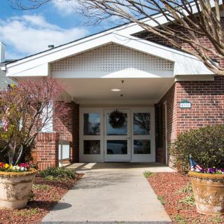 Entrance to a brick building with surrounding plants on a sunny day.