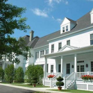 A white residential building with a porch and landscaping.