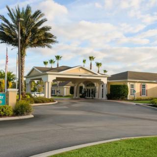 A welcoming entrance to a building surrounded by palm trees on a cloudy day.