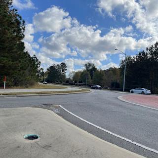 A quiet, tree-lined street intersection under a partly cloudy sky.