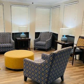 A cozy lounge area featuring patterned chairs, a yellow ottoman, and soft lighting.