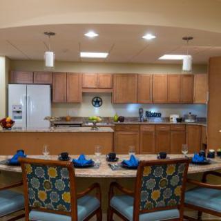A modern kitchen and dining area with wooden cabinets and a set table.