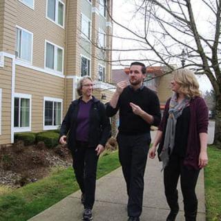 Three people walking together along a path near a building.