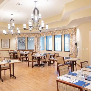 A bright and inviting dining room with multiple tables, chairs, and elegant chandeliers.