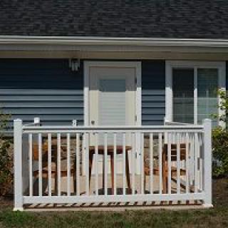 A small porch with white railings and patio furniture in front of a house.
