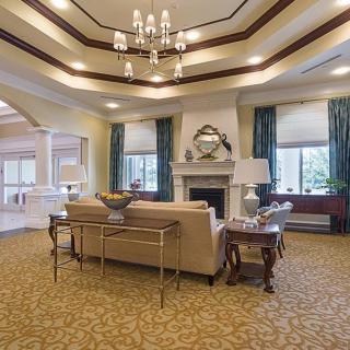 A spacious and elegantly designed living room with a chandelier, fireplace, and large windows.