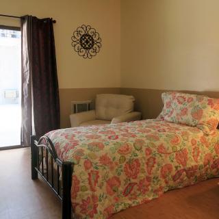 A cozy bedroom with floral bedding and a comfortable chair by the window.