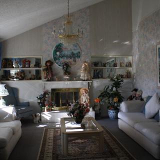 A cozy living room featuring a fireplace, decorated with dolls and elegant furniture.