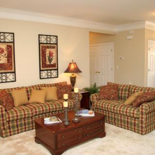 A cozy living room featuring two plaid sofas, a wooden coffee table, decorative lamps, and wall art.