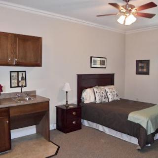 A cozy bedroom featuring a comfortable bed, a nightstand, and a small desk area.