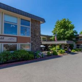 A modern hotel building with stone accents and well-maintained landscaping under a clear blue sky.