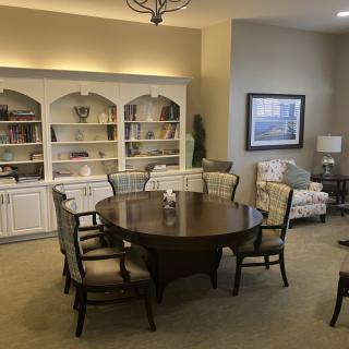 A cozy dining area with a round table surrounded by chairs, adjacent to bookshelves and tasteful decor.