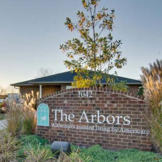 The Arbors assisted living facility sign with a brick base and surrounding greenery.