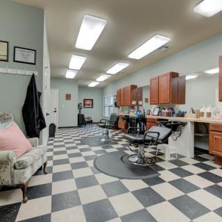 A modern barbershop with a checkered floor, styling chairs, and mirrors along the wall.