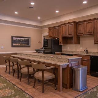 A modern kitchen interior with a large island, wooden cabinets, and seating.