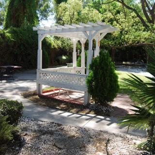 A charming white gazebo surrounded by lush greenery in a serene garden setting.