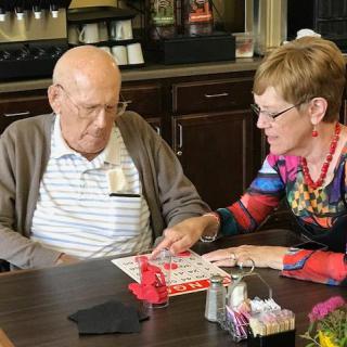An elderly man receives assistance while playing bingo.