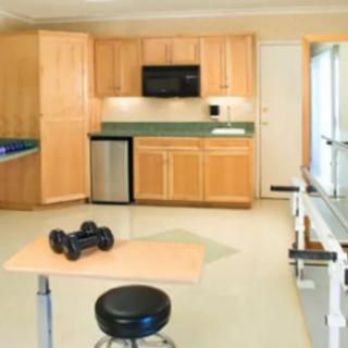 A modern kitchen with wooden cabinetry, featuring exercise equipment and a small stool.