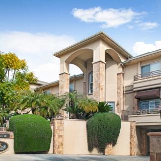 A modern, elegant residential building with well-maintained landscaping and a clear blue sky.