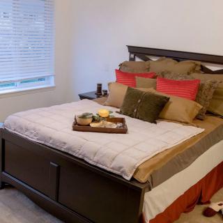 A neatly made bed with decorative pillows and a tray in a cozy bedroom.