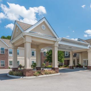 A large residential building with a covered entrance on a sunny day.