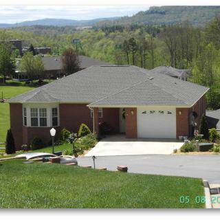 A suburban house with a spacious driveway, surrounded by greenery and scenic views.