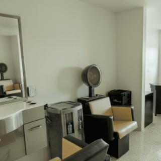 Interior of a salon with chairs and hair-drying equipment.