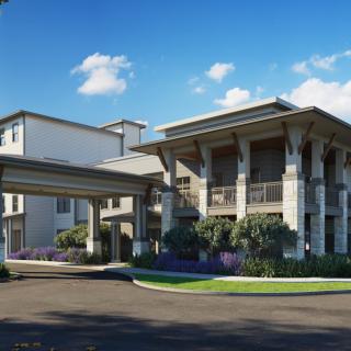 A modern residential building with landscaped surroundings and a covered entrance.