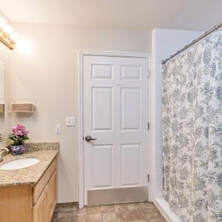 A contemporary bathroom featuring a shower curtain, vanity with sink, and decorative elements.