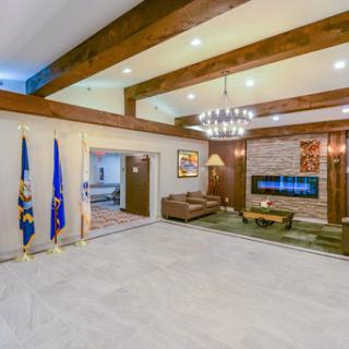 A spacious and elegantly designed living room featuring a modern fireplace and rustic wood beams.