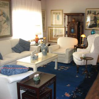 A cozy living room with white furniture and a blue rug.