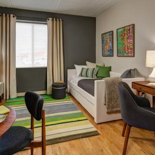 A modern living room with a daybed, wooden flooring, and colorful decor.