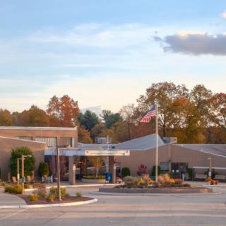A hospital building with an entrance surrounded by trees under a partly cloudy sky.