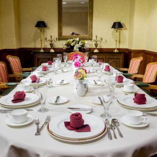A formally set dining table with elegant dinnerware and napkins in a cozy interior.