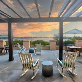 A peaceful patio with rocking chairs overlooking a lake at sunset.