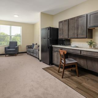 A modern apartment interior featuring a kitchen with wooden cabinets and a cozy living area.