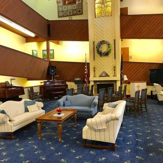 A spacious lobby with comfortable seating, featuring sofas, a fireplace, and a piano.