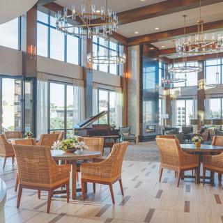 A luxurious dining area with modern decor, featuring a grand piano and large windows.